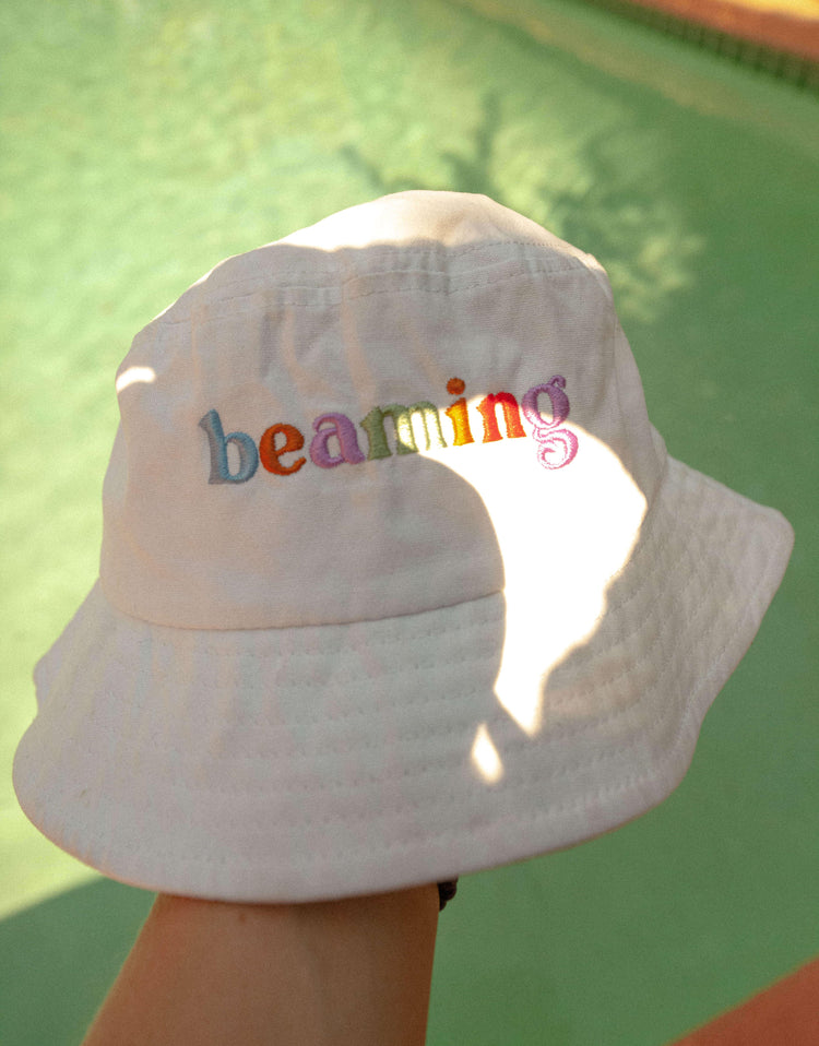 person holding sunbeam bucket hat by pool